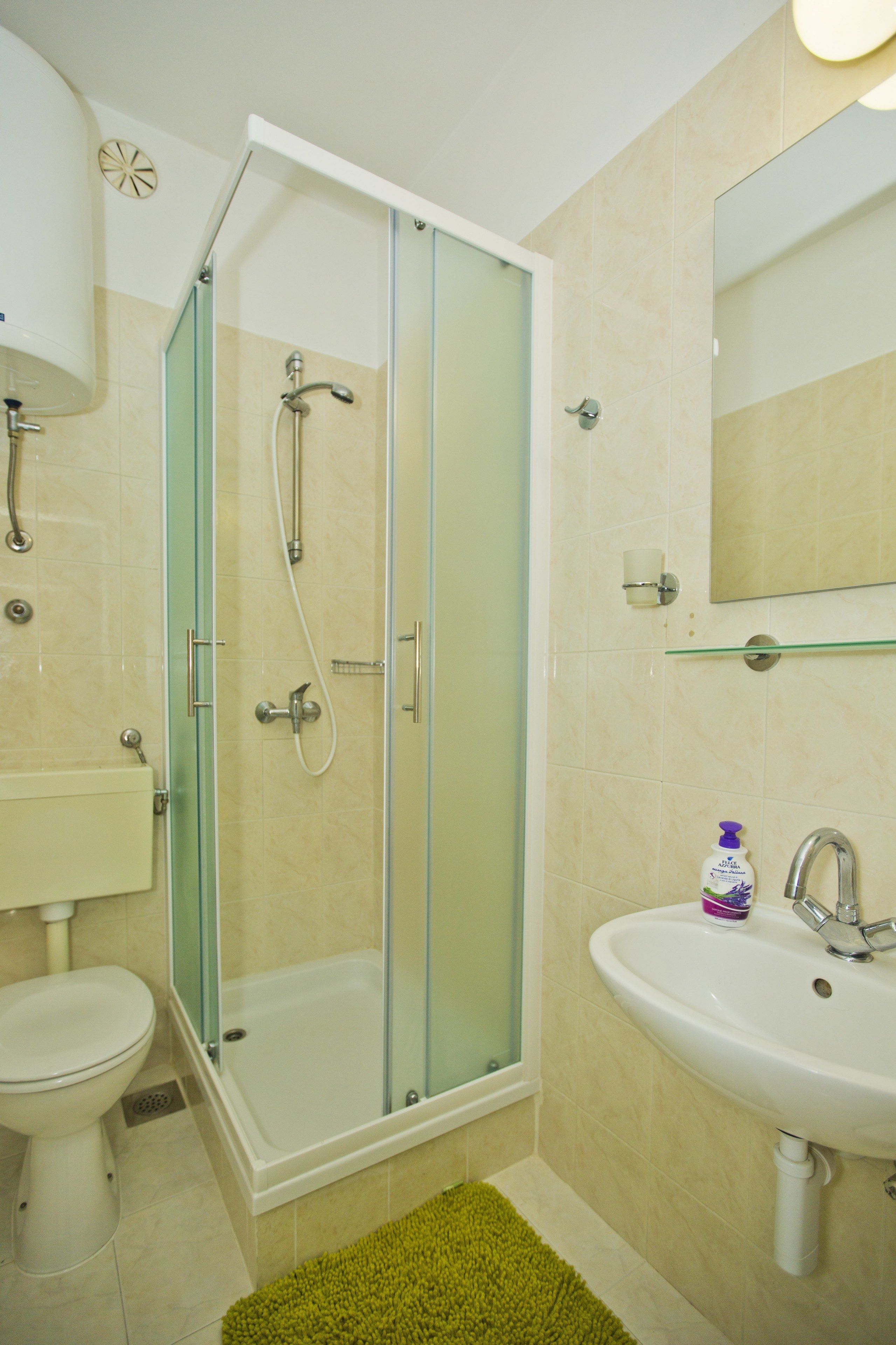 Un baño con ducha de vidrio, un lavabo blanco y un inodoro.
