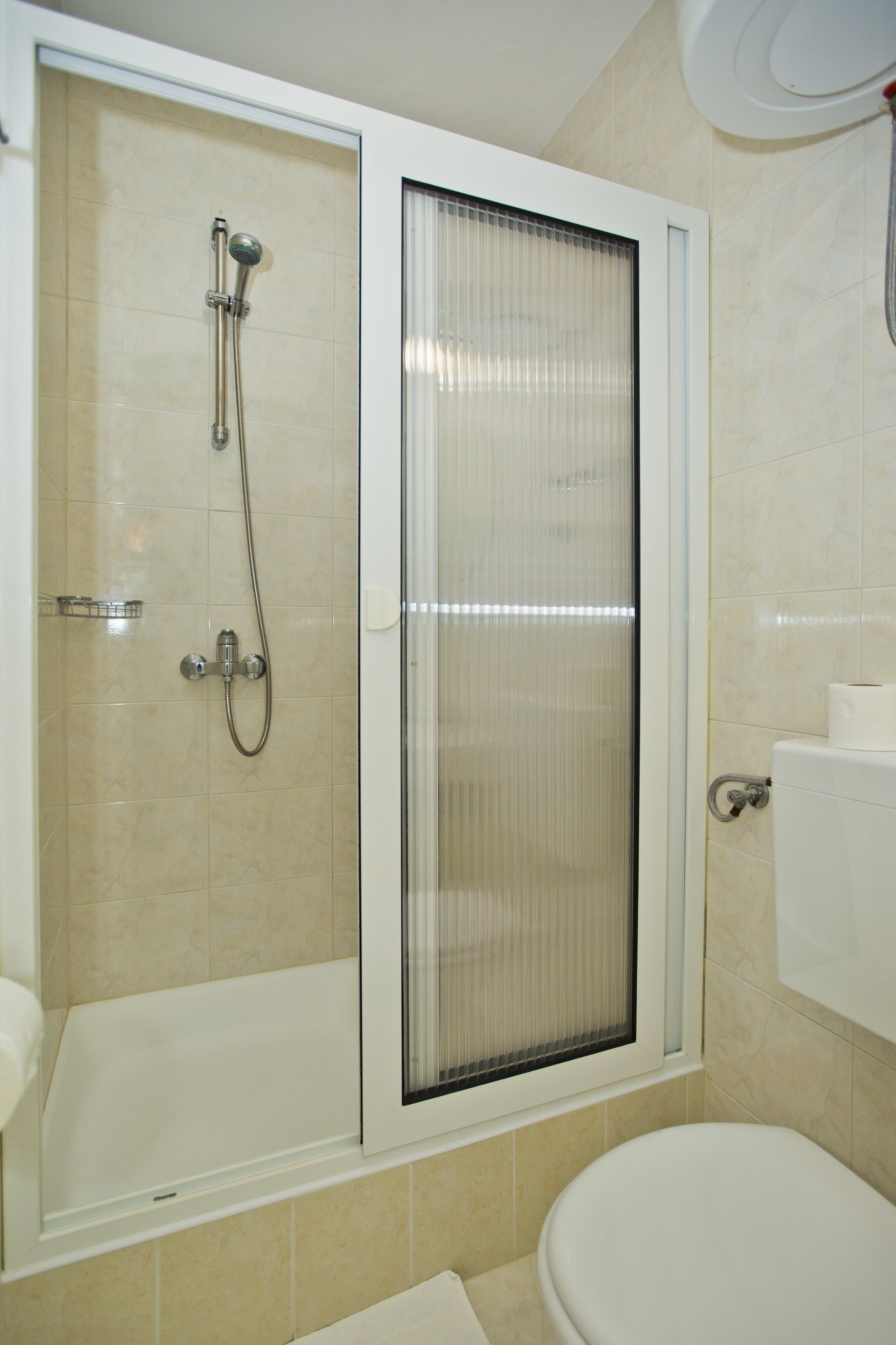 A bathroom with a glass-enclosed shower, a toilet, and a sink.
