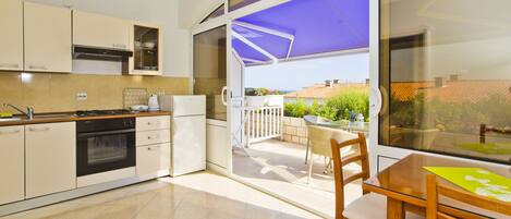 A modern kitchen with a dining area, a balcony with a view, and a large window.