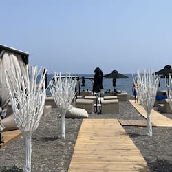 Sulla spiaggia, sabbia scura, lettini da mare, ombrelloni