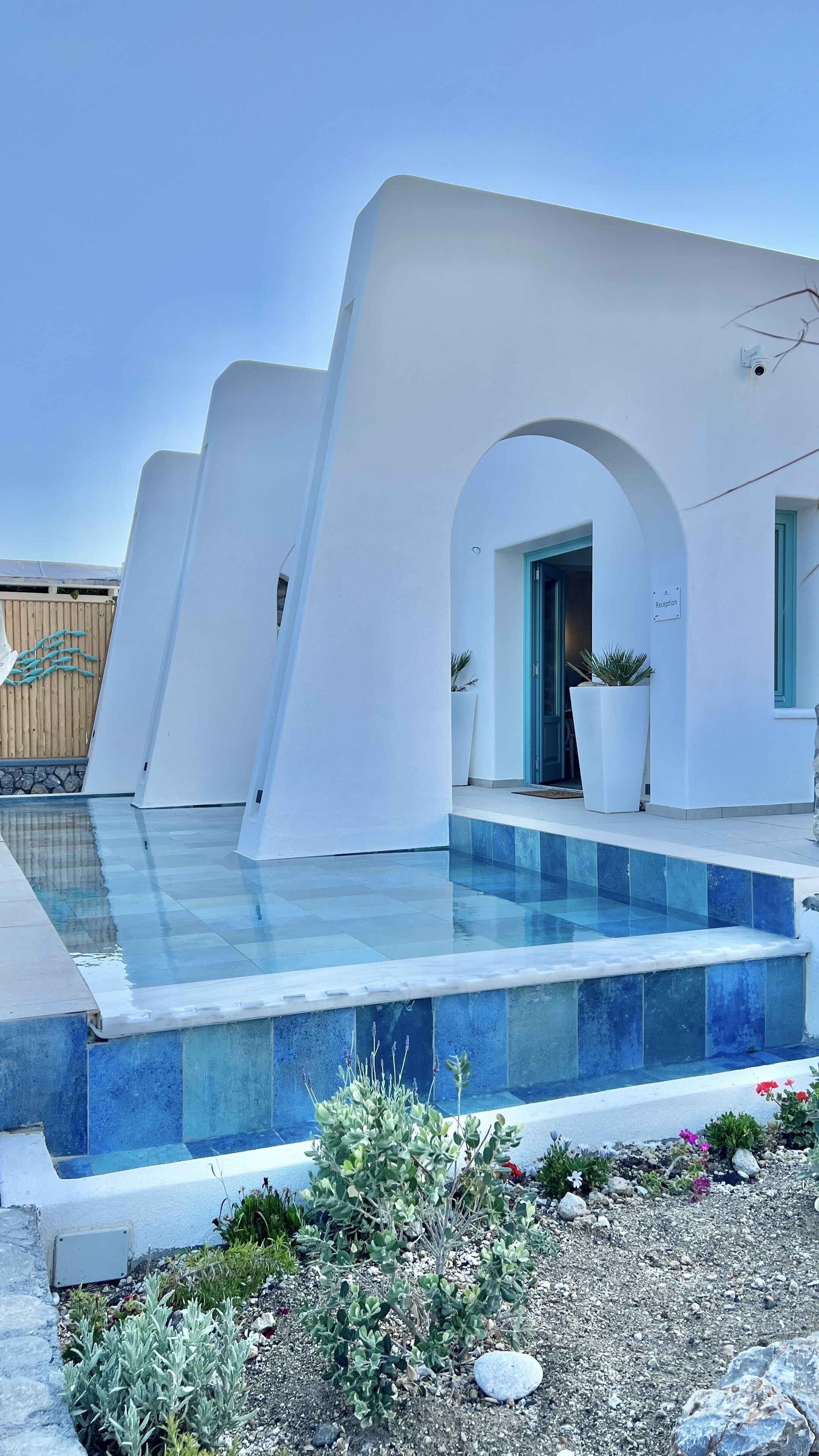 A modern building with a pool, white walls, and a reception area.