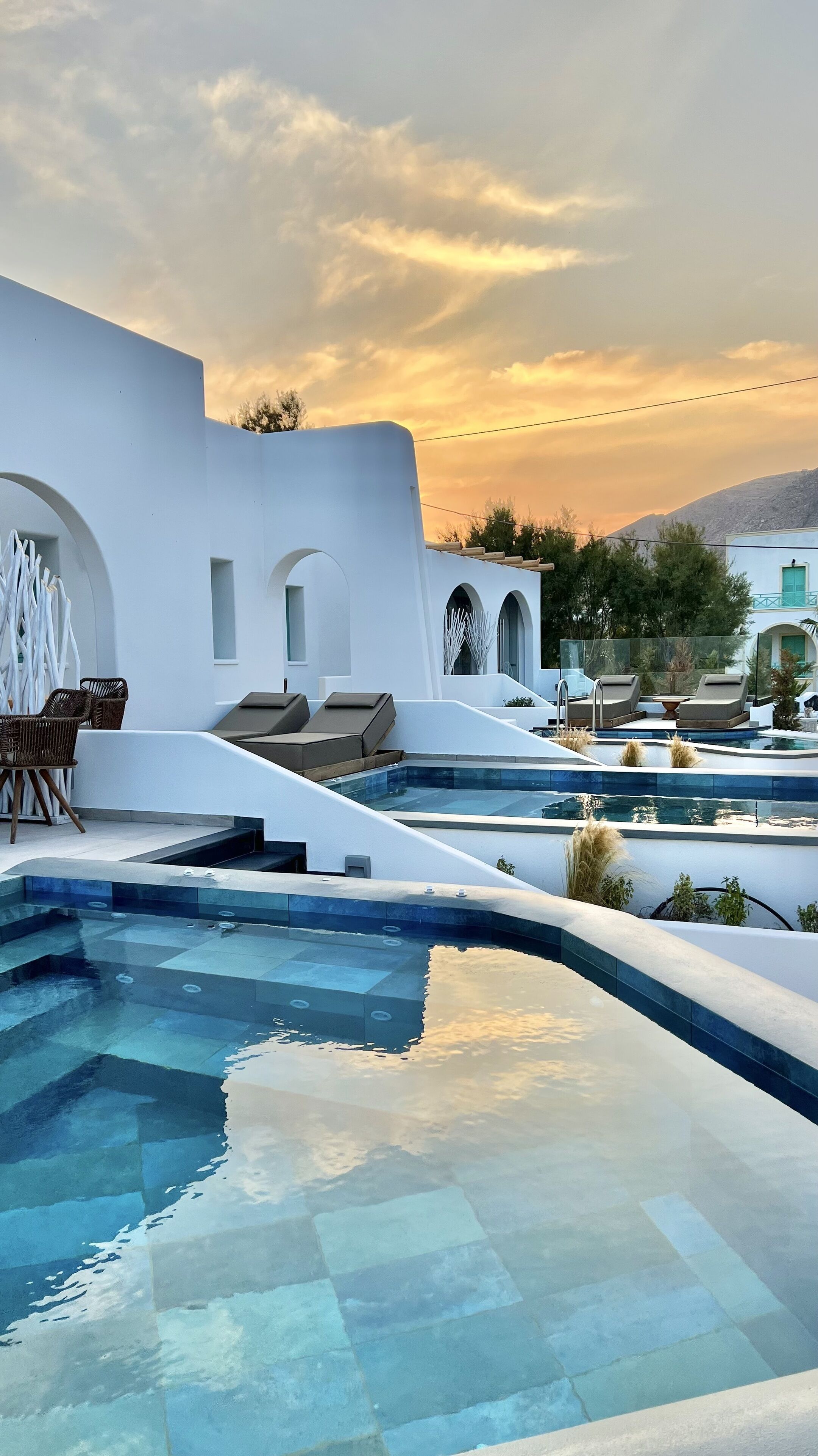 A modern pool area with lounge chairs and a clear view of the sky.