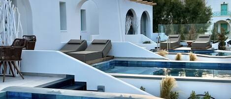 A modern pool area with lounge chairs and a clear view of the sky.