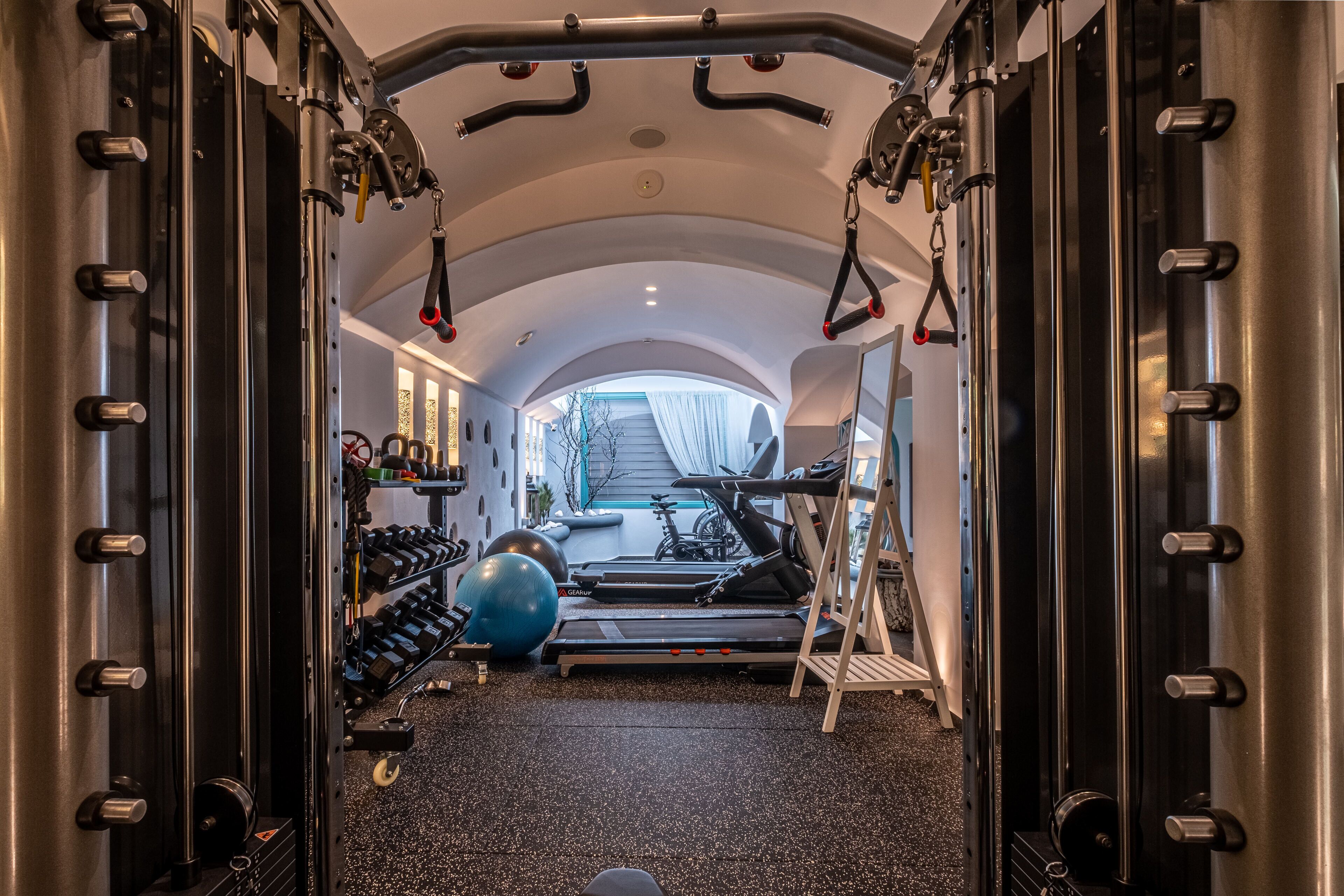 A gym with a treadmill, weights, and exercise balls.