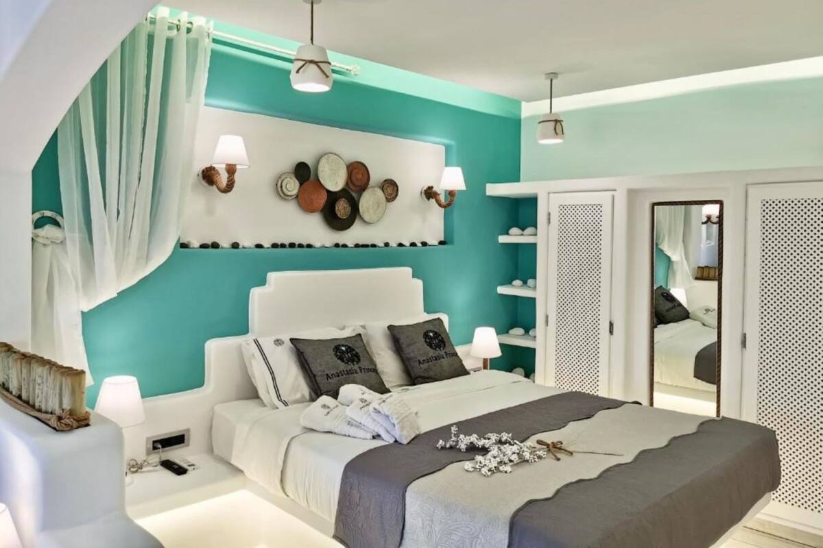 Een moderne slaapkamer met tealwanden, een wit hoofdeinde en een decoratief kunstwerk aan de muur.
