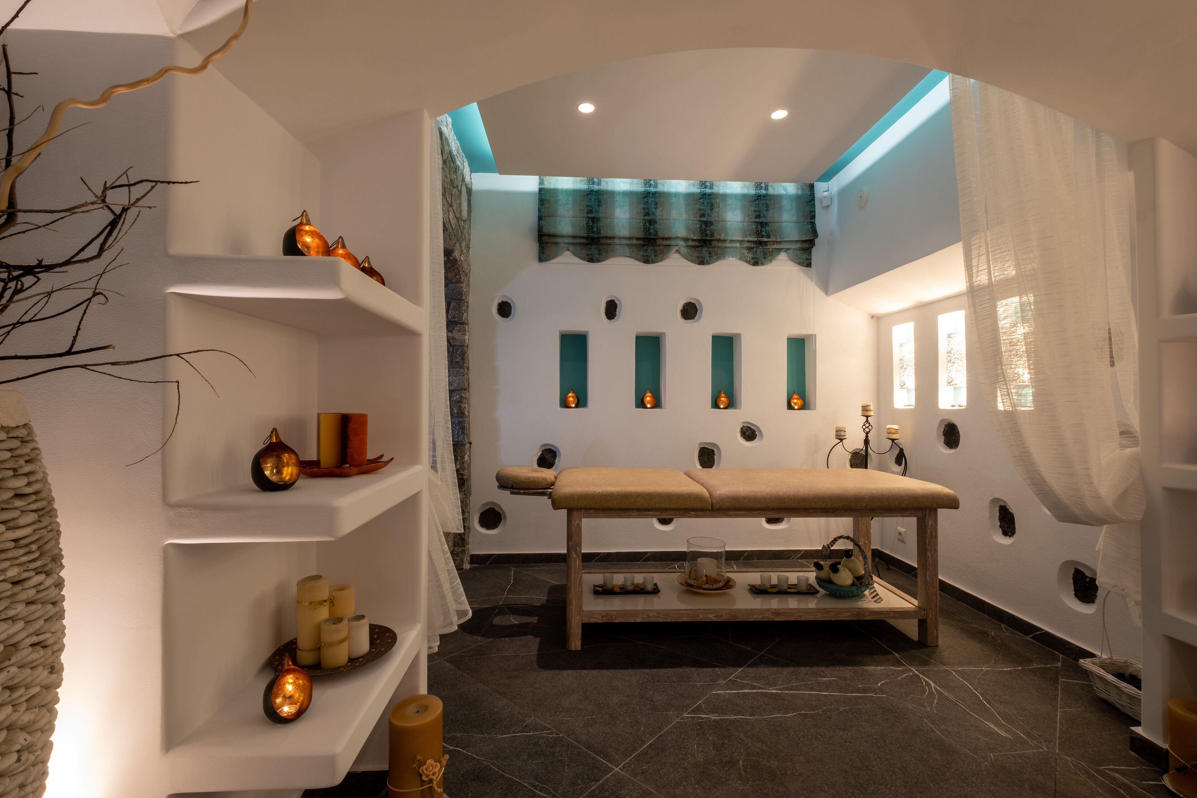 A spa room with a wooden bench, shelves with candles, and decorative items.