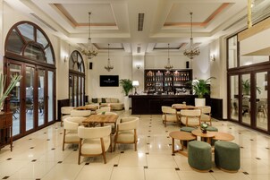 Un vestíbulo de hotel con una zona de bar, asientos y ventanas amplias.