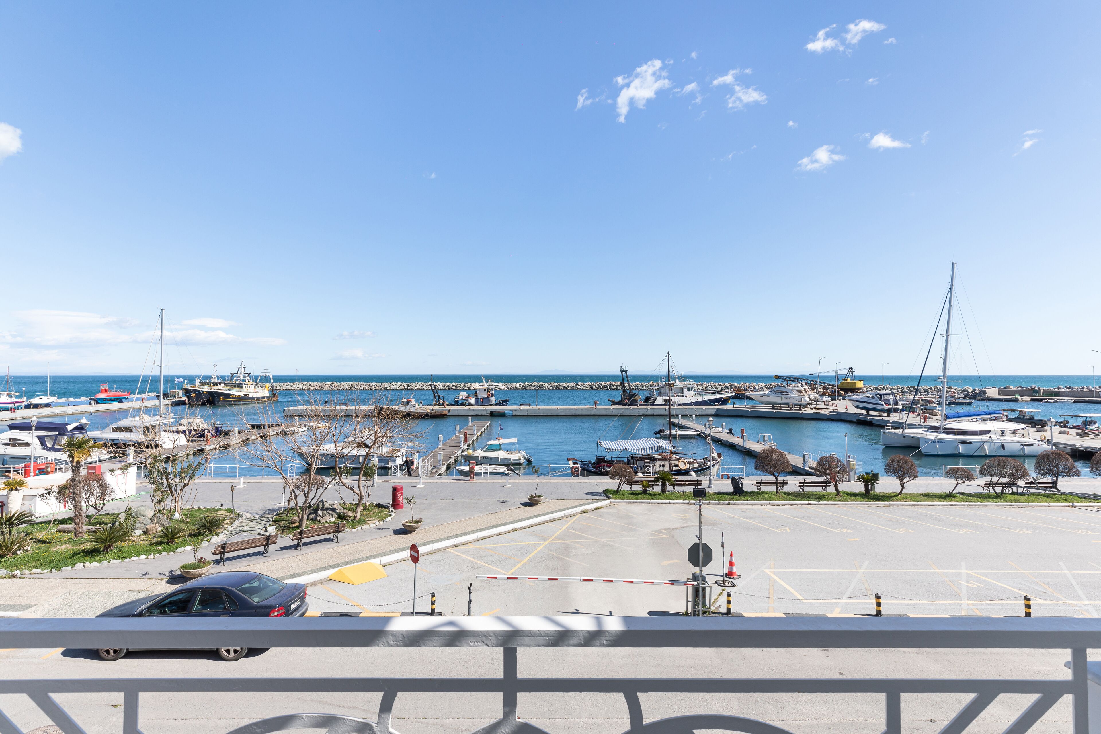 A marina with boats docked, a car parked, and a clear blue sky.