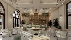 Un lobby amplio con zona de bar, disposición de asientos y un gran ventanal que proporciona luz natural.
