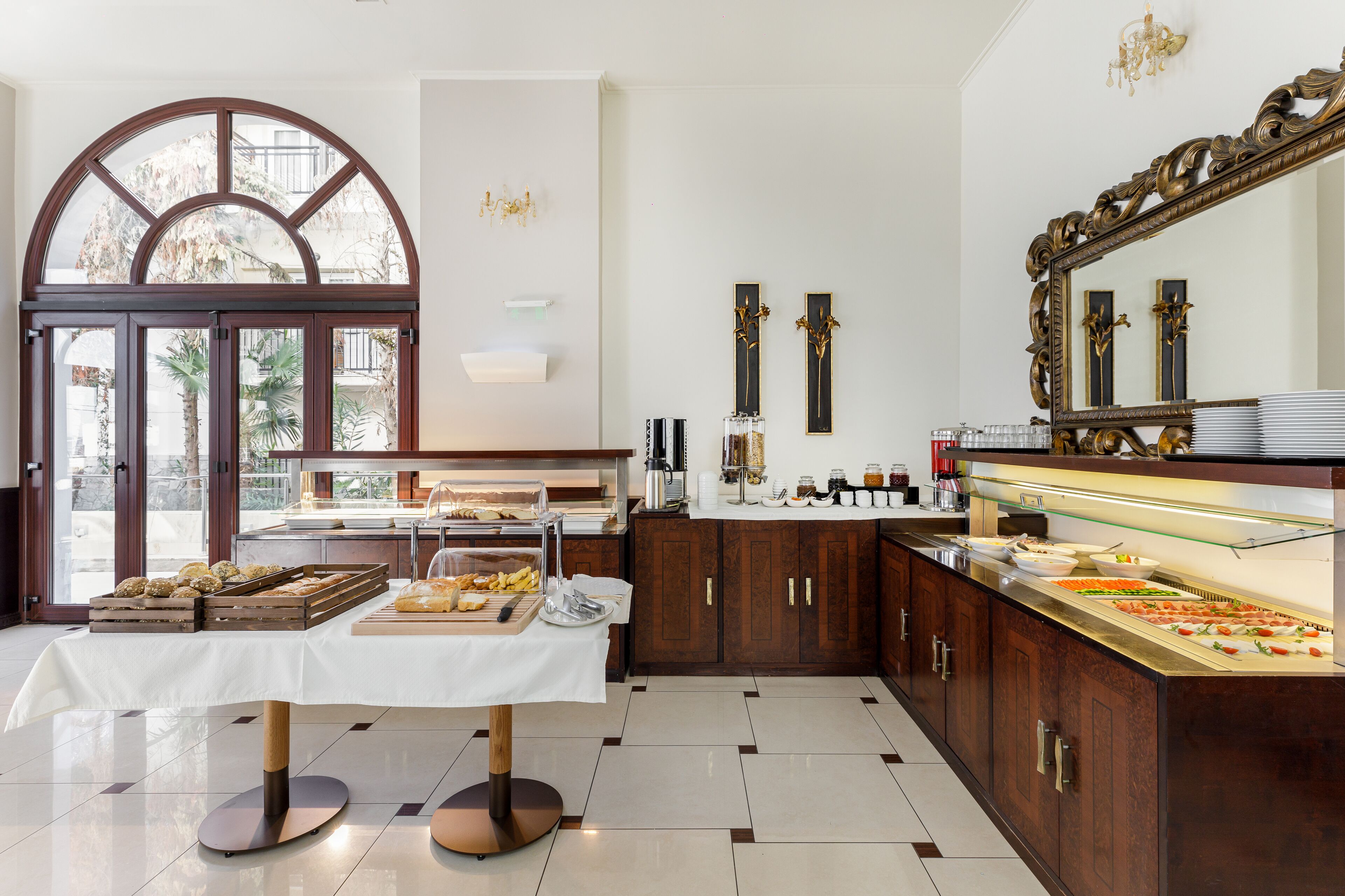 A buffet area with a variety of food items, a large mirror, and a view through a glass door.