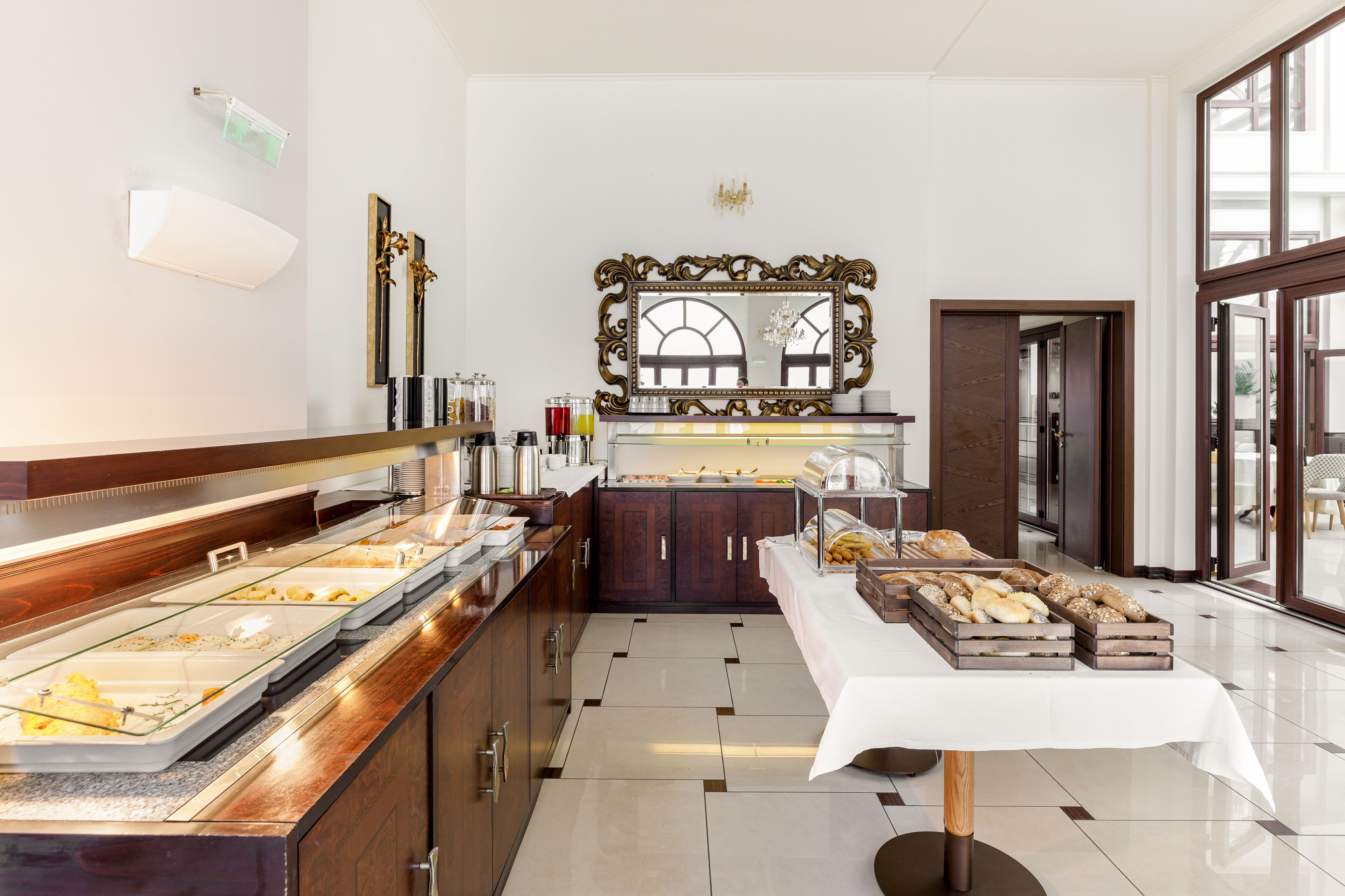 A buffet area with various food items, a mirror, and a chandelier.