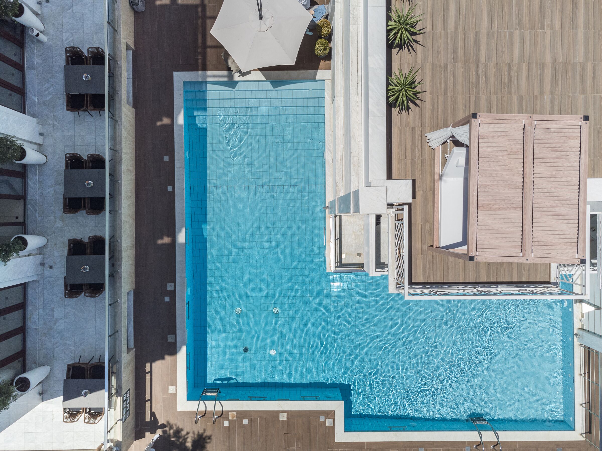 An aerial view of a hotel with a swimming pool, outdoor seating, and a wooden deck area.