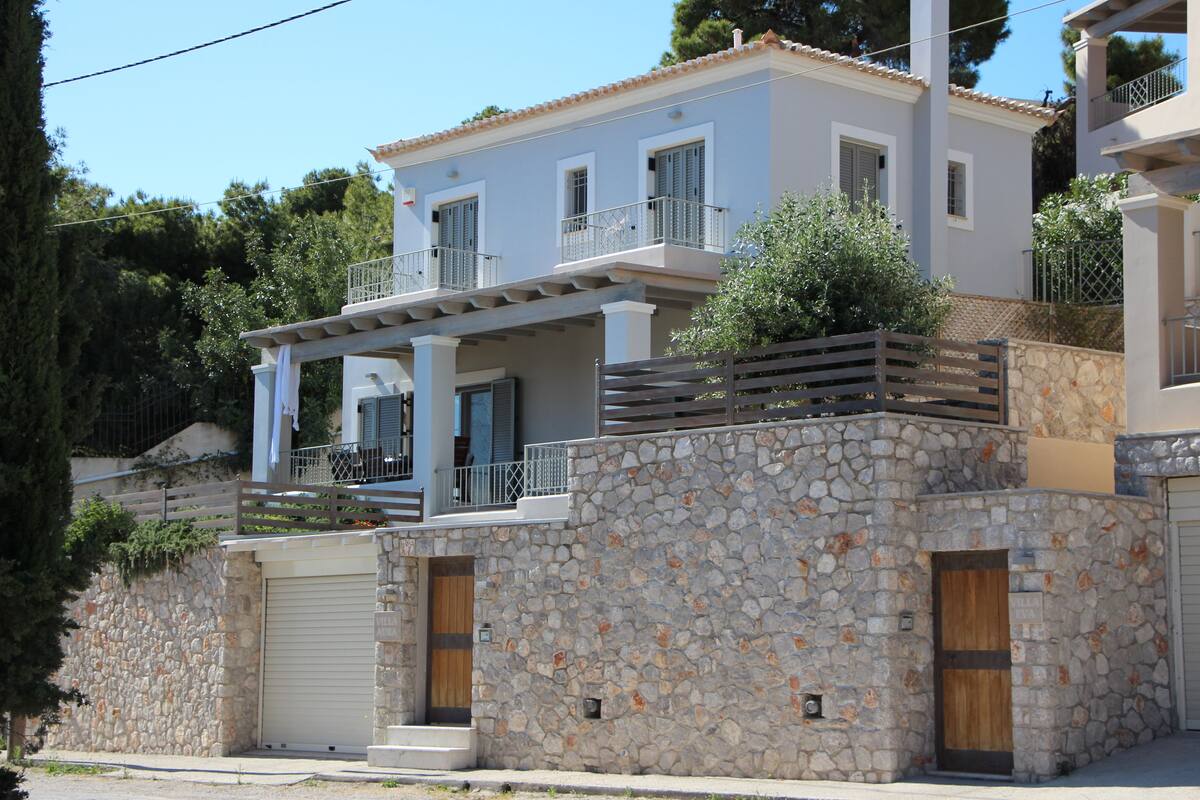 A two-story house with a stone facade, a balcony, and a garage door.