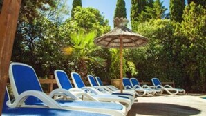 Une terrasse en bois avec des chaises longues et un parasol en chaume.