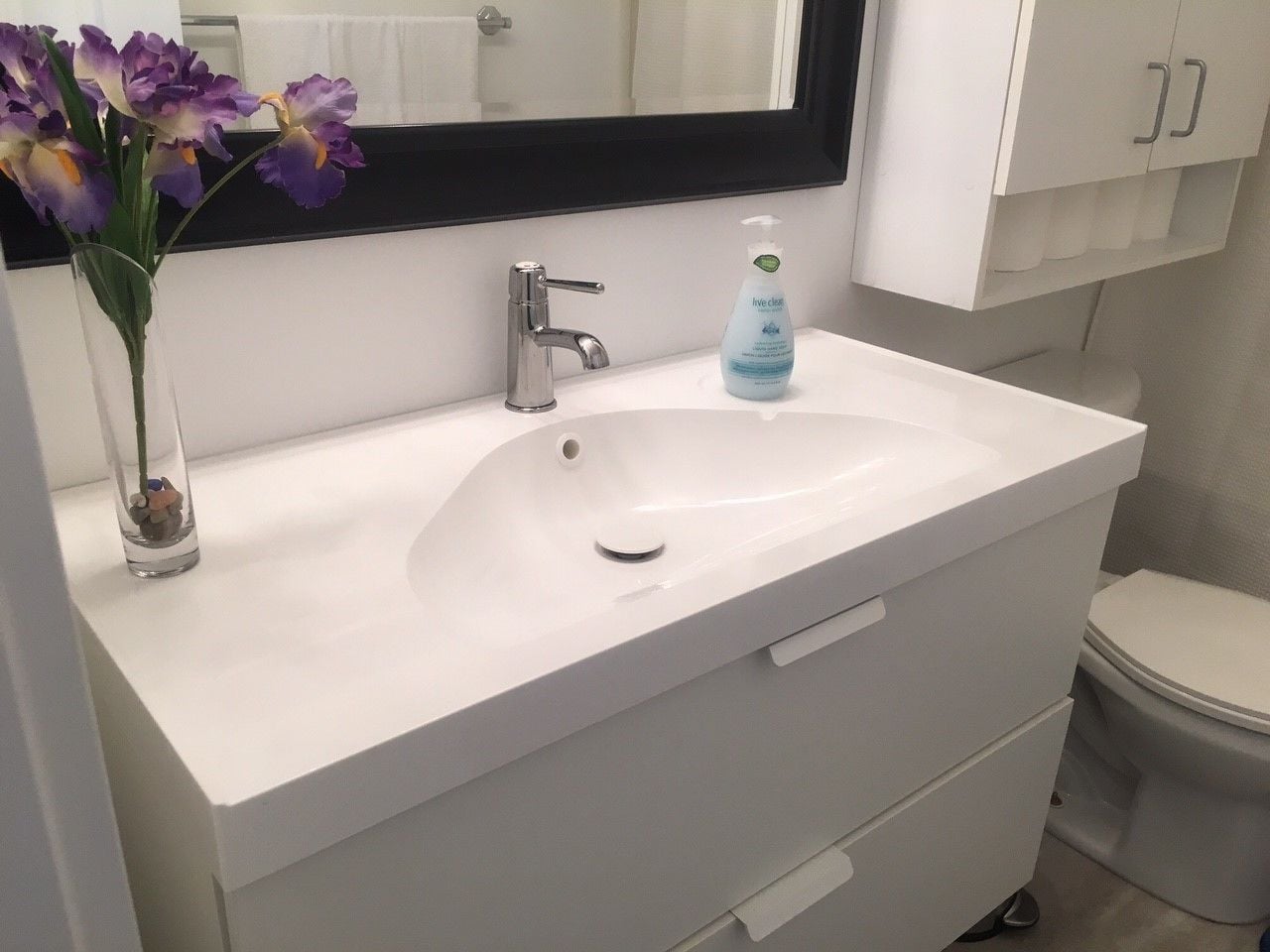 A bathroom with a white sink, a mirror above it, and a toilet.