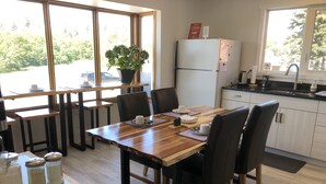 Una cocina moderna con una mesa de comedor, sillas, un refrigerador y una ventana con vistas al exterior.