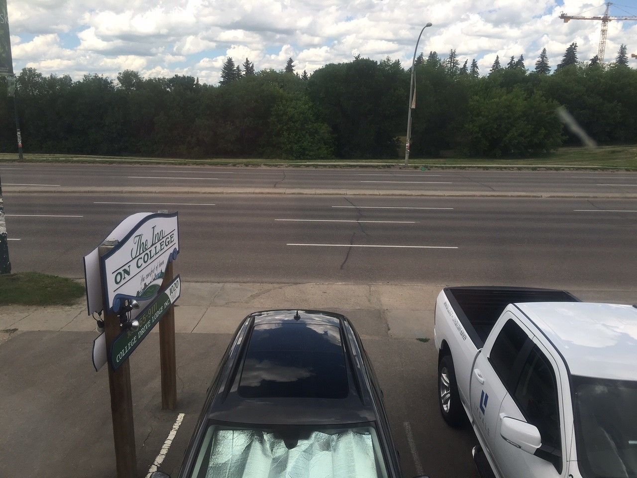 A sign for The Inn on College Drive, indicating a location near a road with parked vehicles.