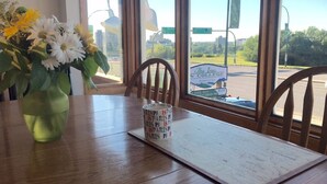 Una mesa de madera con un jarrón de flores, una taza y un menú.