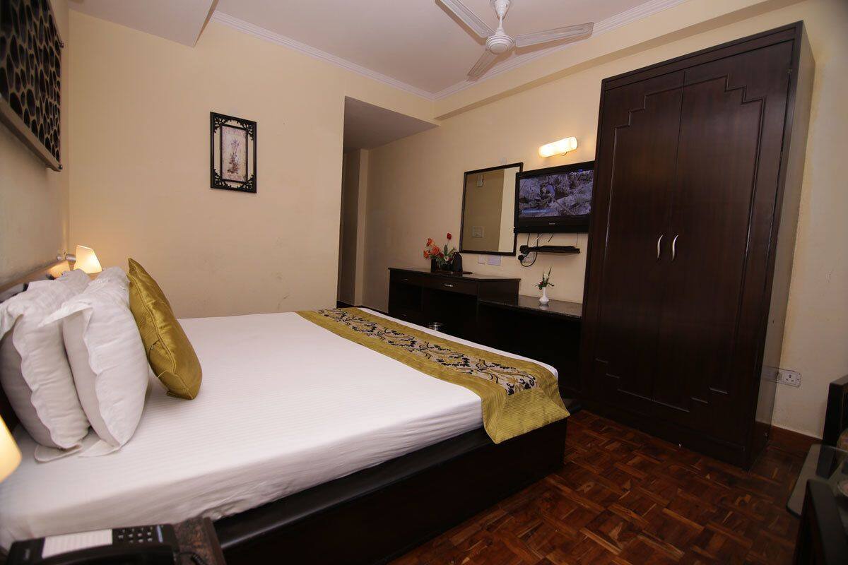 A bedroom with a bed, a dresser, a mirror, a television, and a wardrobe.