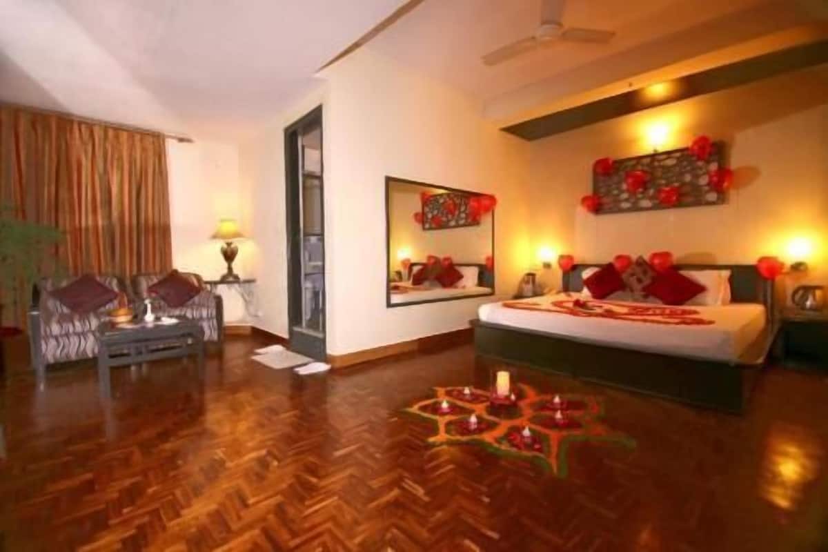 A hotel room with a bed, a chair, a small table, and a mirror.