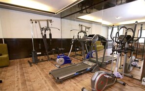 A gym with cardio machines, weight machines, and a mirrored wall.