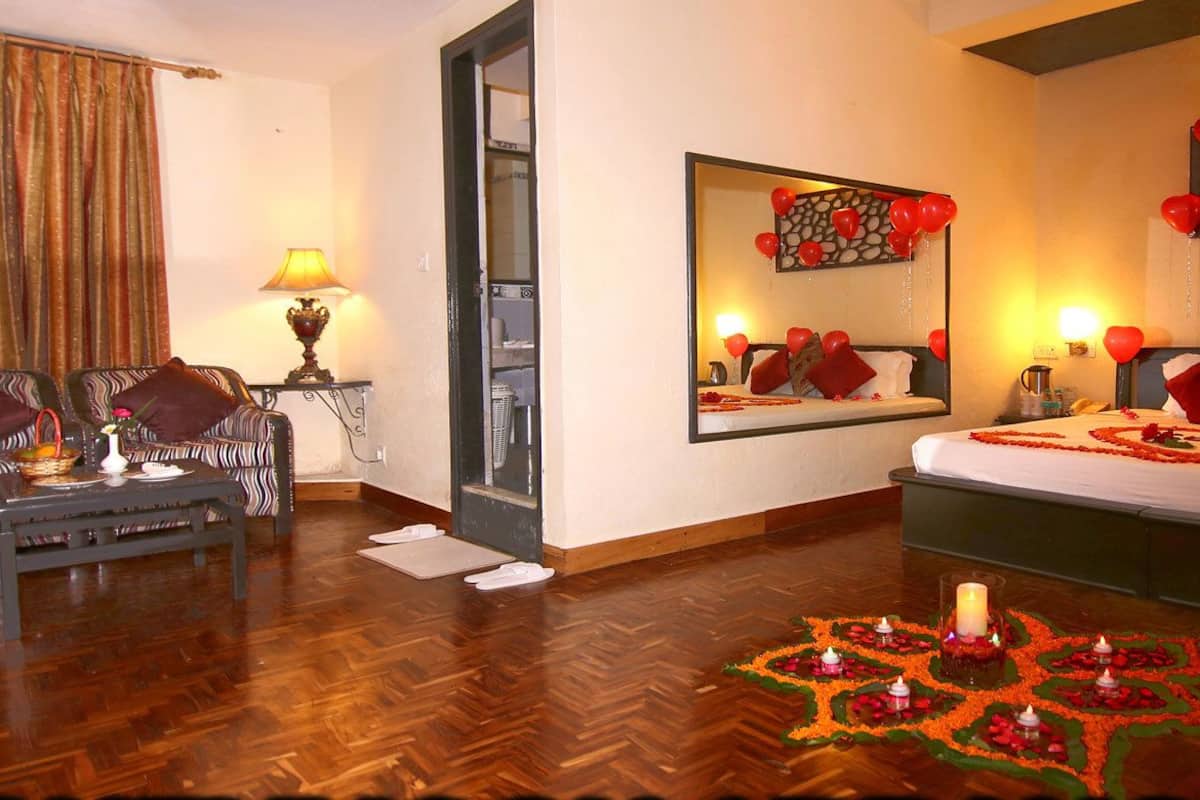 A hotel room with a bed, a sofa, a coffee table, and a mirror.