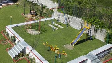 Children can play and exercise safely in this playground area featuring a slide, swings, and climbing equipment.