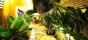 A pathway lined with tropical plants leading to an outdoor seating area with umbrellas. - Thapae Boutique House (Chiang Mai)