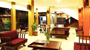 Et hotellobby med trappe, siddeområde og et fjernsyn.