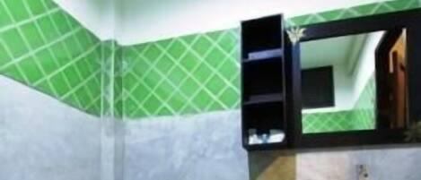 Un baño pequeño con inodoro, lavamanos y paredes con azulejos verdes.