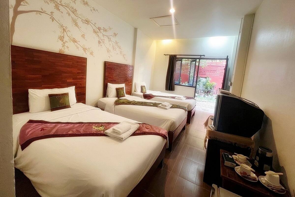 Une chambre d’hôtel avec deux lits, une télévision et une petite table sur laquelle se trouve un plateau avec des articles pour le petit-déjeuner.