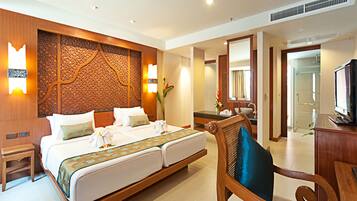 A hotel room with a large bed, a wooden headboard, a television, and a bathroom visible through an open door.