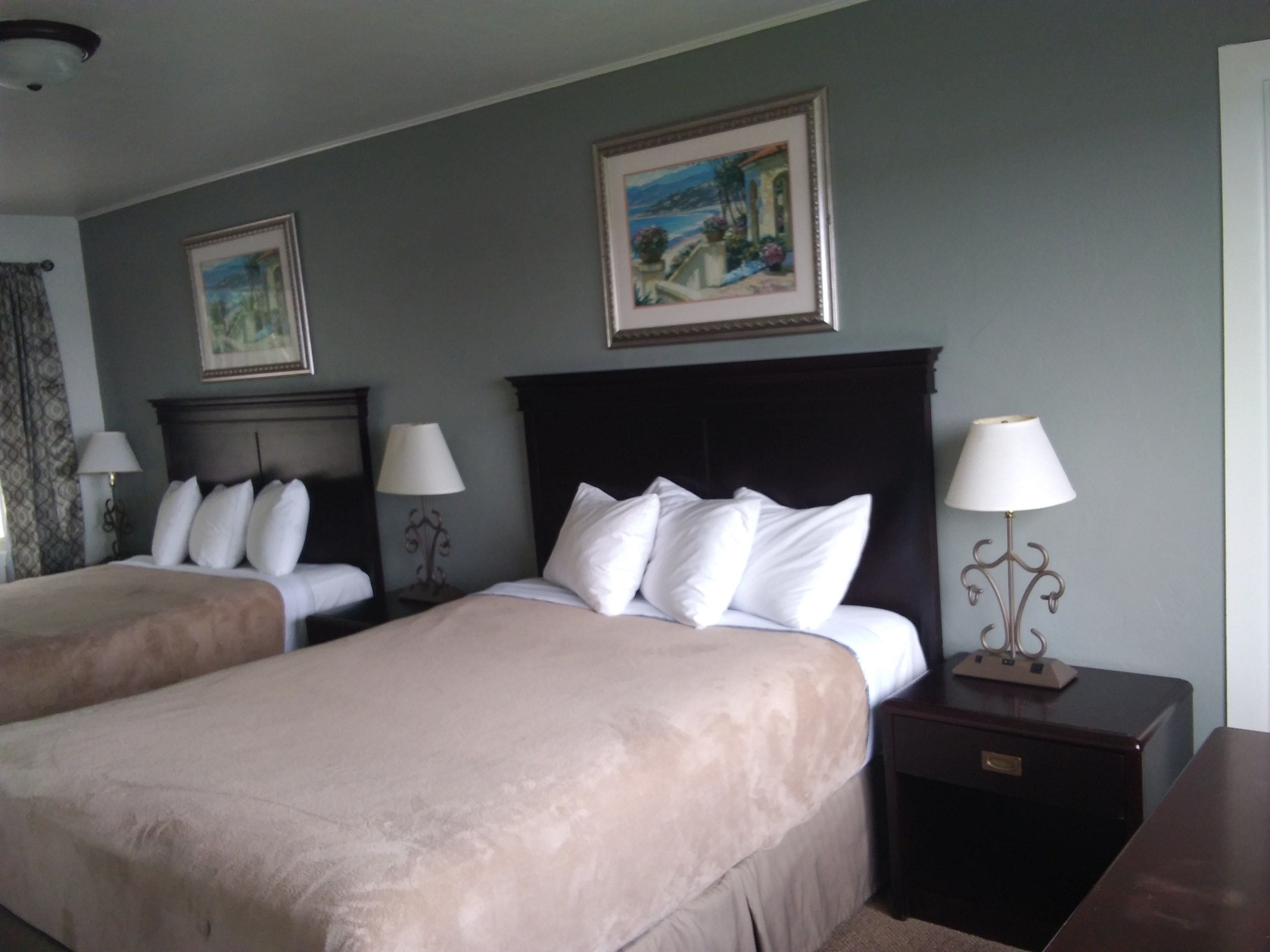 Une chambre d’hôtel avec deux lits, une table de chevet avec une lampe et un tableau encadré au mur.