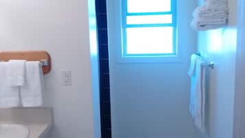 A narrow bathroom with a white sink, a window, and a towel rack.