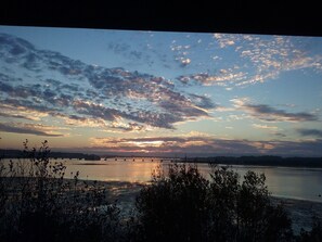 Un atardecer sobre una superficie de agua tranquila, con un puente a lo lejos.