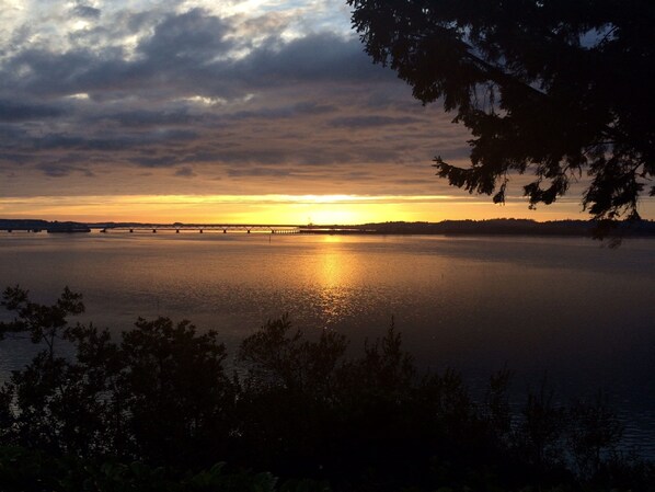 A sunset over a calm lake with a bridge in the distance. - Bay Bridge Motel (North Bend)