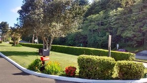 A well-maintained roadside with neatly trimmed hedges, a mailbox, and a speed limit sign. - Bay Bridge Motel (North Bend)