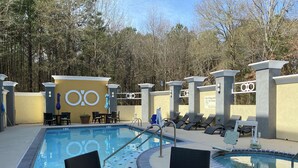 A pool area with lounge chairs, a table, and a sign indicating no lifeguard on duty. - Hampton Inn by Hilton Leesville Fort Polk (Leesville)