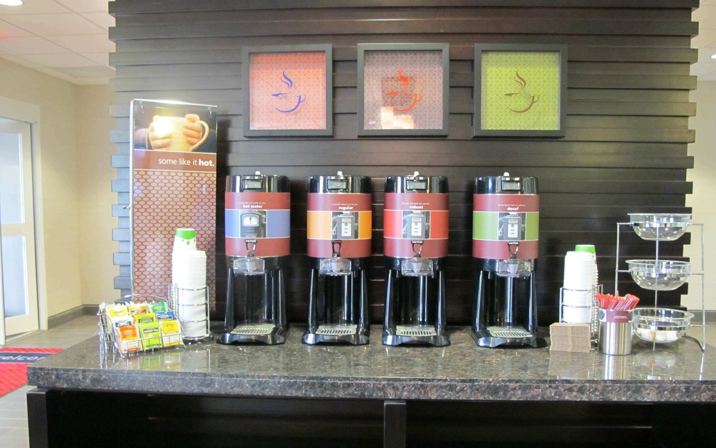 A coffee station with multiple dispensers, a water cooler, and a sign indicating hot beverages.
