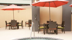 An outdoor pool area with a hot tub, surrounded by tables and chairs with umbrellas. - Hampton Inn by Hilton Leesville Fort Polk (Leesville)