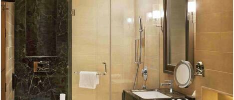 A modern bathroom with a glass-enclosed shower, a marble vanity, and a large mirror.