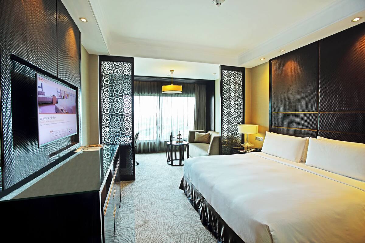 Een hotelkamer met een groot bed, een tv op een standaard, een bureau en een stoel.