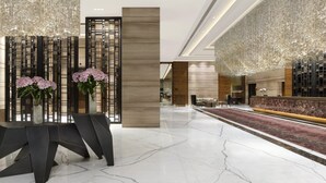 A modern lobby with a reception desk, seating area, and decorative elements like a vase of flowers and a hanging chandelier. - Crowne Plaza New Delhi Mayur Vihar Noida by IHG (New Delhi)