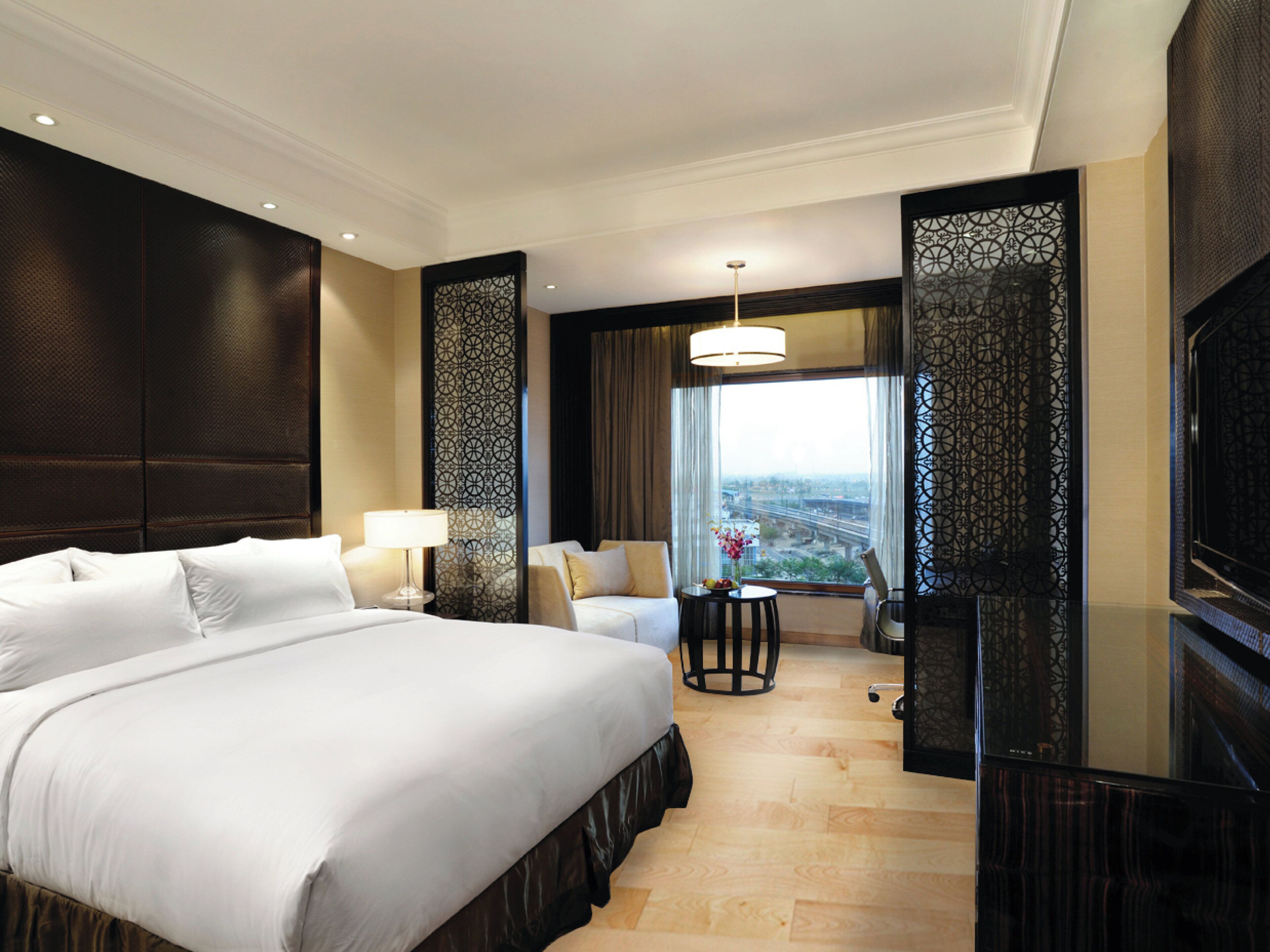 A hotel room with a large bed, a desk, a chair, and a television.