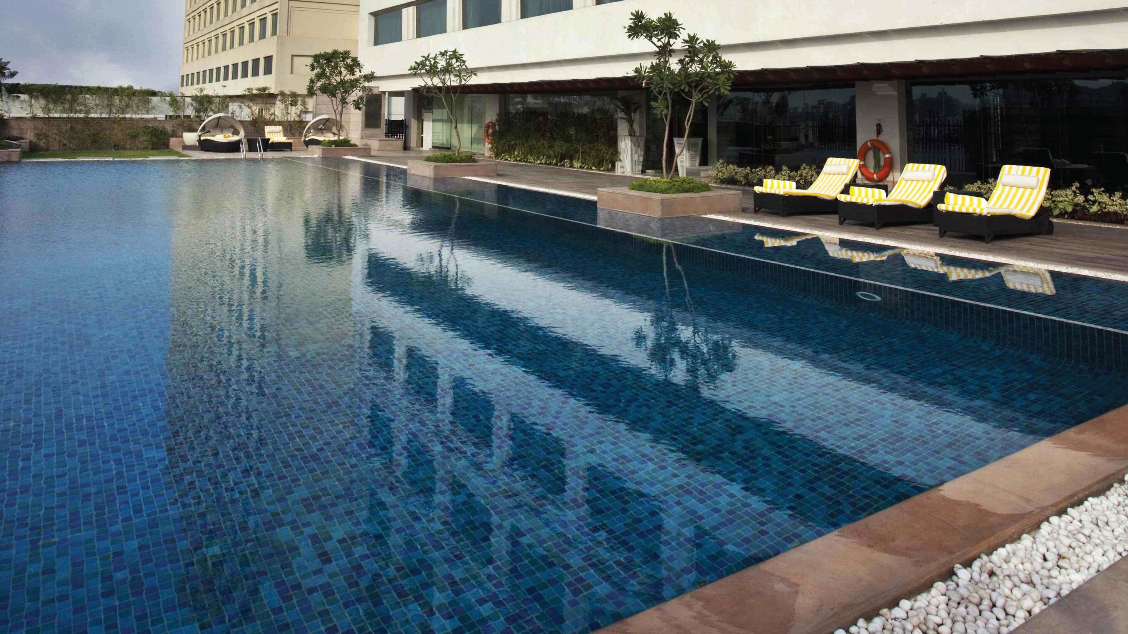 A swimming pool with lounge chairs and a building in the background.