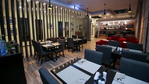 A modern restaurant with a bar area, wooden flooring, and contemporary furniture.