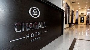 A modern hotel entrance with a dark wood facade and a logo featuring a house.