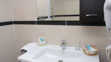 A bathroom with a white sink, dark cabinets, a mirror, and a hairdryer.