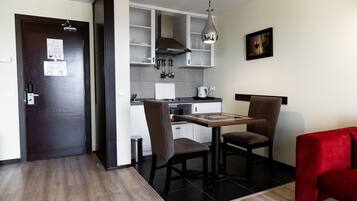 A modern kitchen with a dining area, including a table and chairs, a red sofa, and a hanging light fixture.