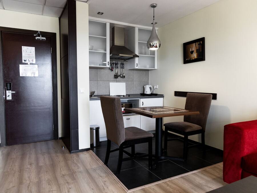 A modern kitchen with a dining area, including a table and chairs, a red sofa, and a hanging light fixture.